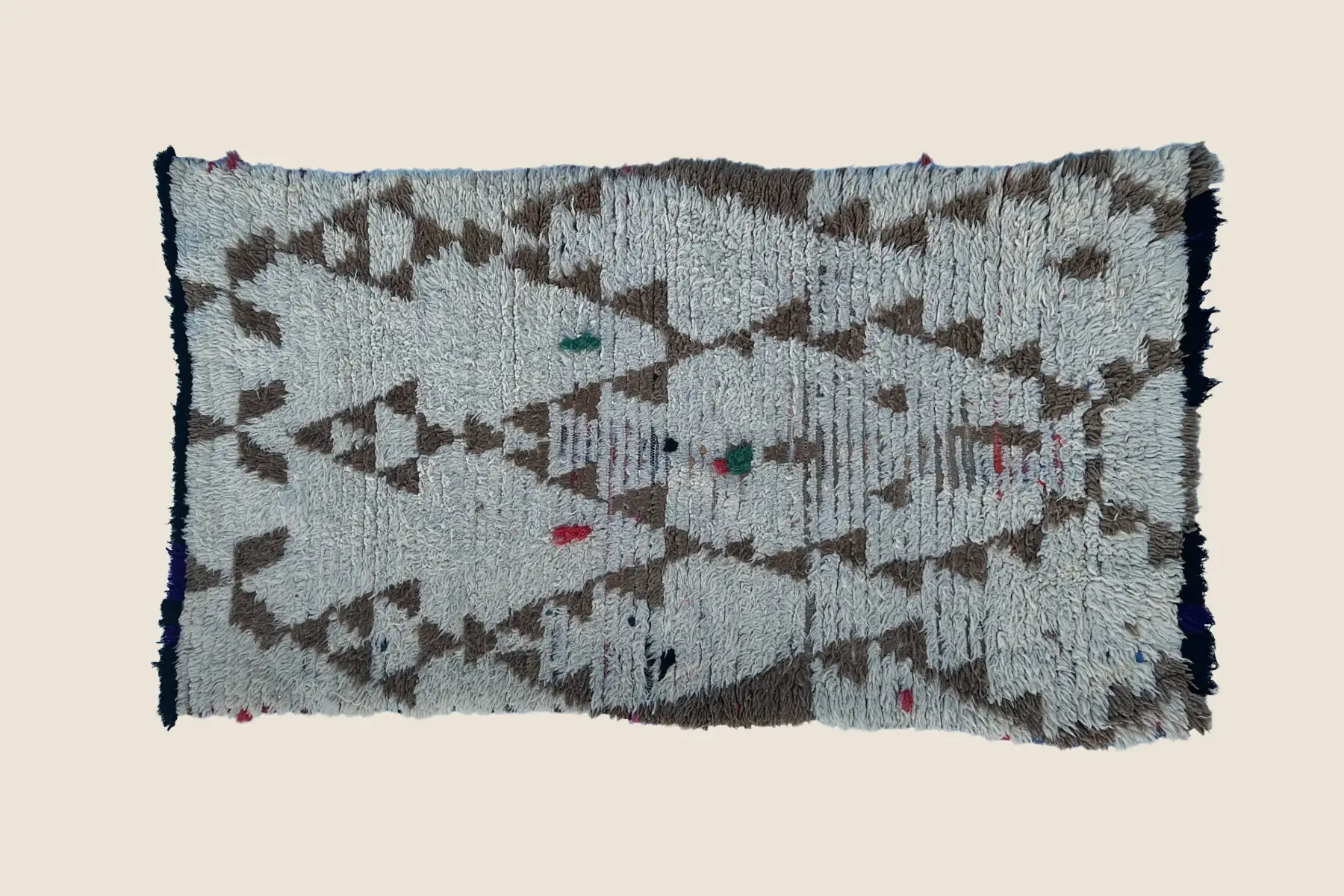 Beni M'Guild hand-knotted wool detail showing navy and brown geometric motifs with light gray background texture