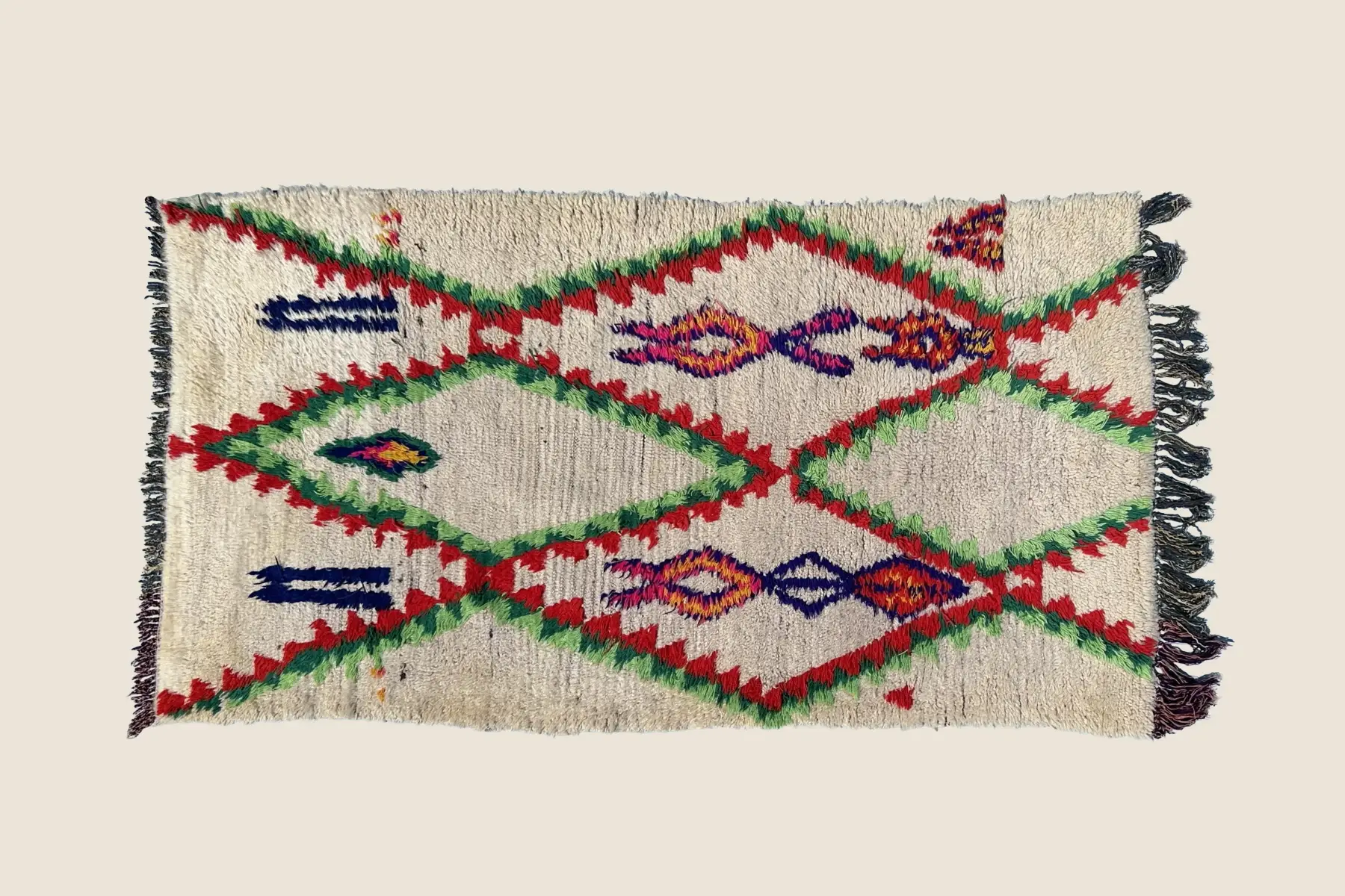Azilal rug detail showing hand-knotted wool texture with geometric motifs in beige, red, teal, and rose