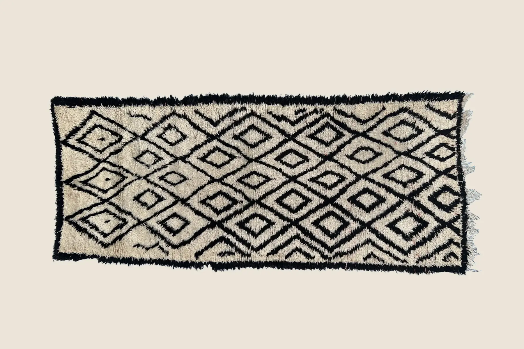Beni M'Guild wool texture showing charcoal geometric motif on warm beige pile - hand-knotted Berber craftsmanship detail