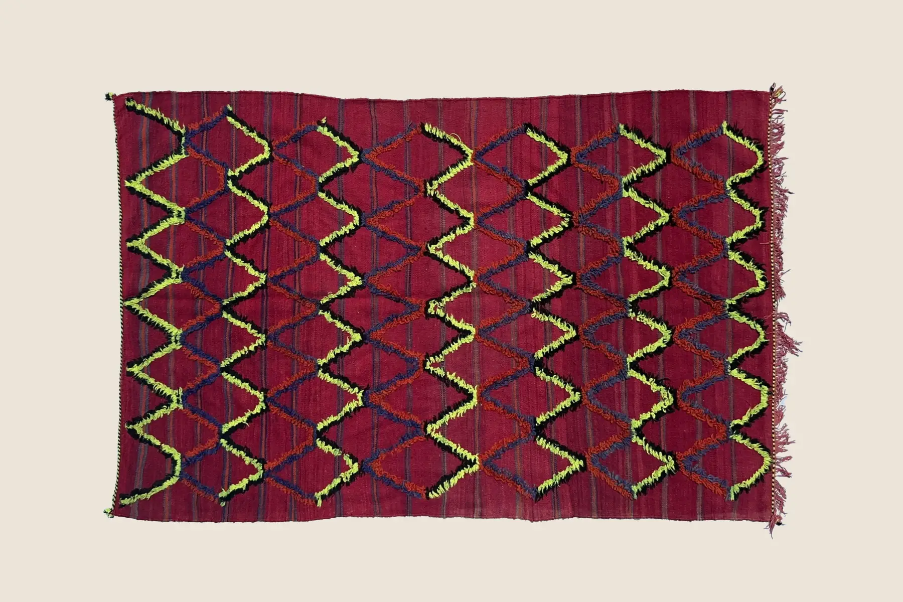 Talsint rug detail showing hand-knotted crimson and violet-gray wool texture with coral accents