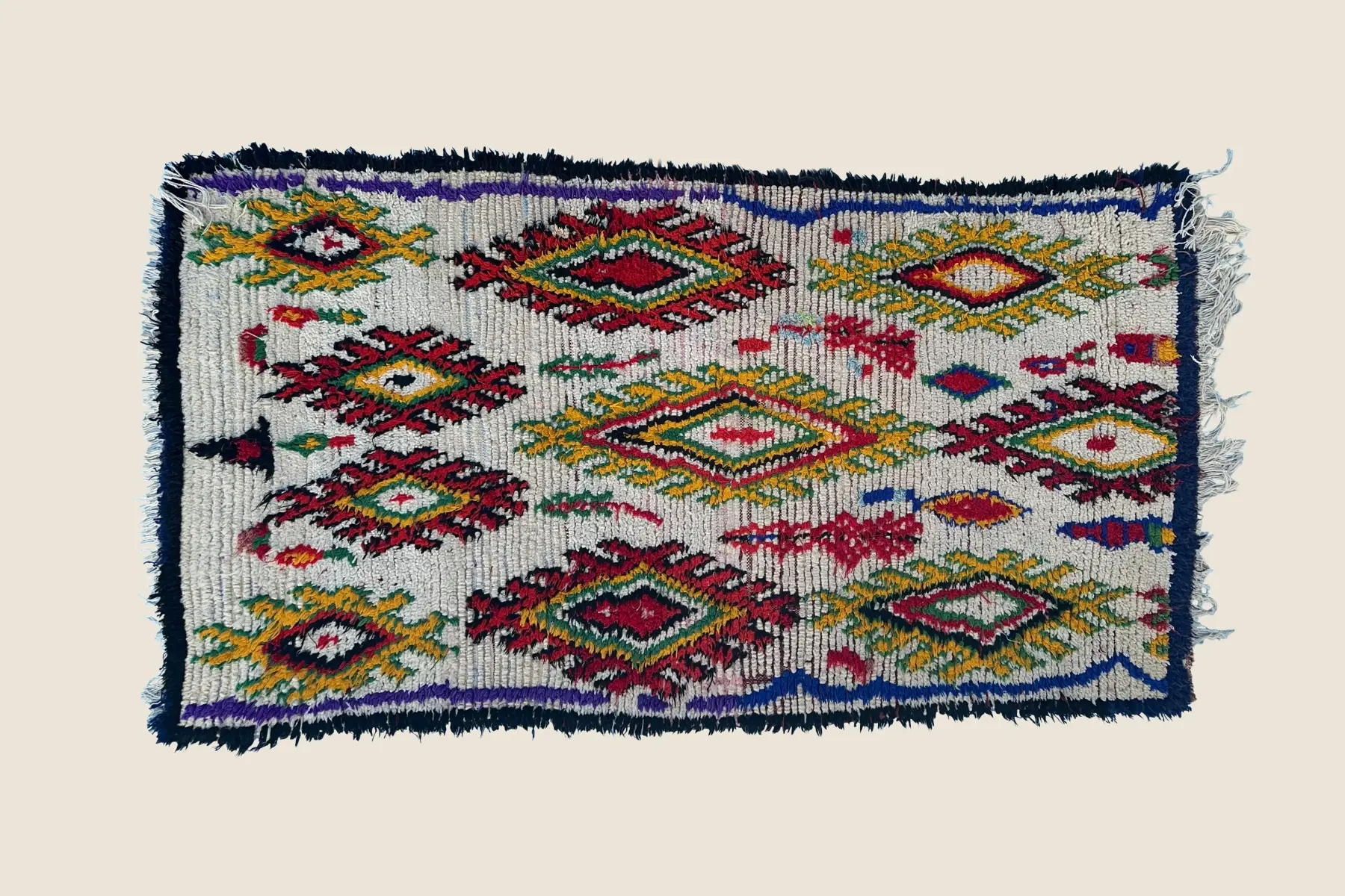 Azilal handwoven wool detail showing vibrant red, gold, and blue geometric motifs with natural dye variations and tight weaving technique