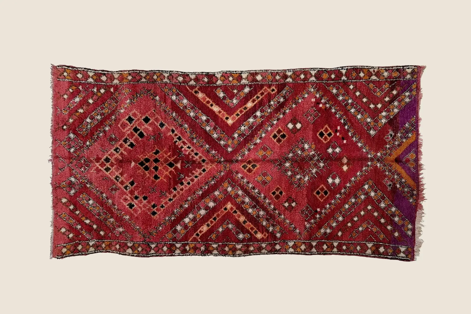 Marmoucha rug detail showing hand-knotted geometric motif with charcoal, magenta, and red wool texture