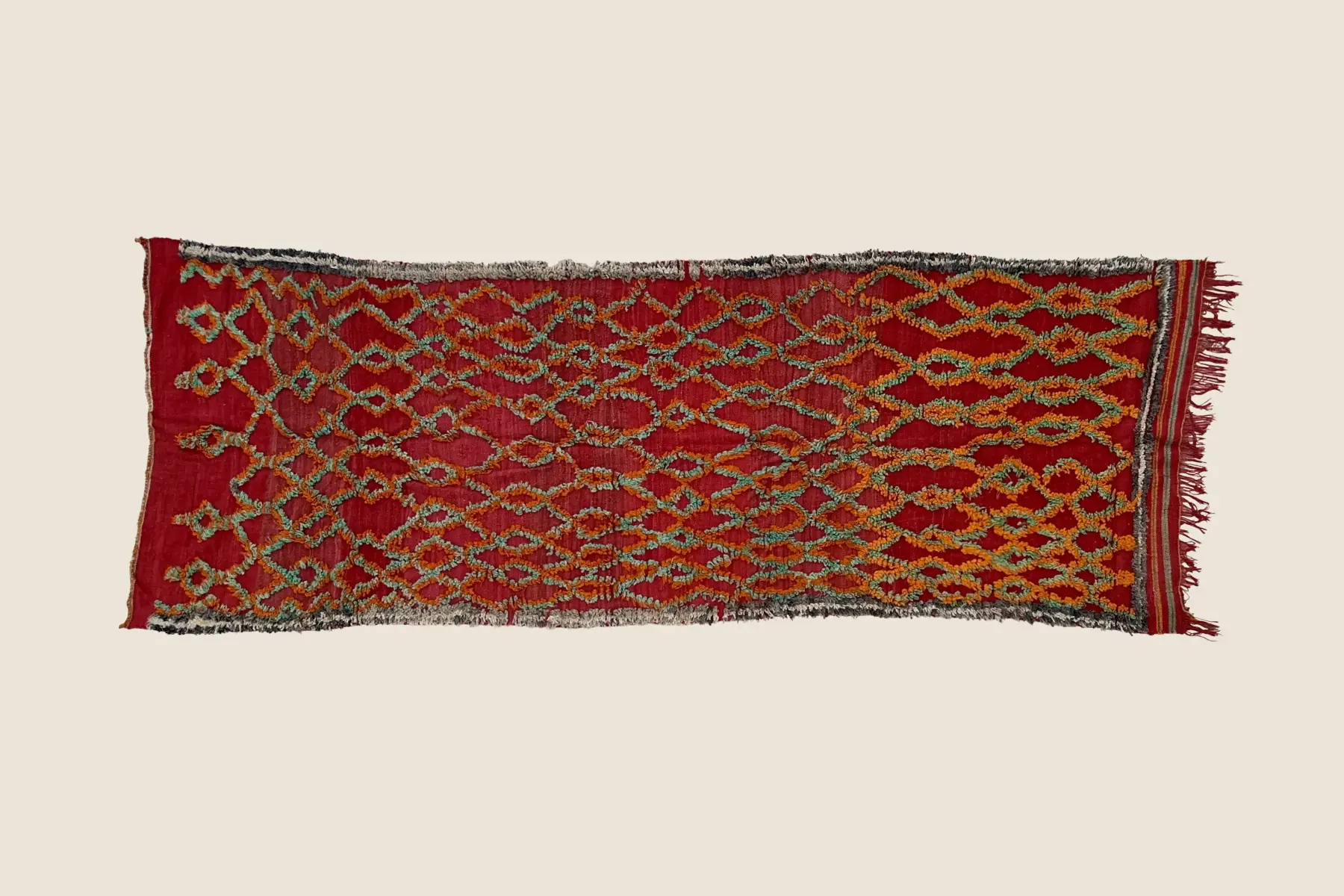 Talsint rug detail showing hand-woven geometric pattern with dark red, warm orange, and beige wool texture