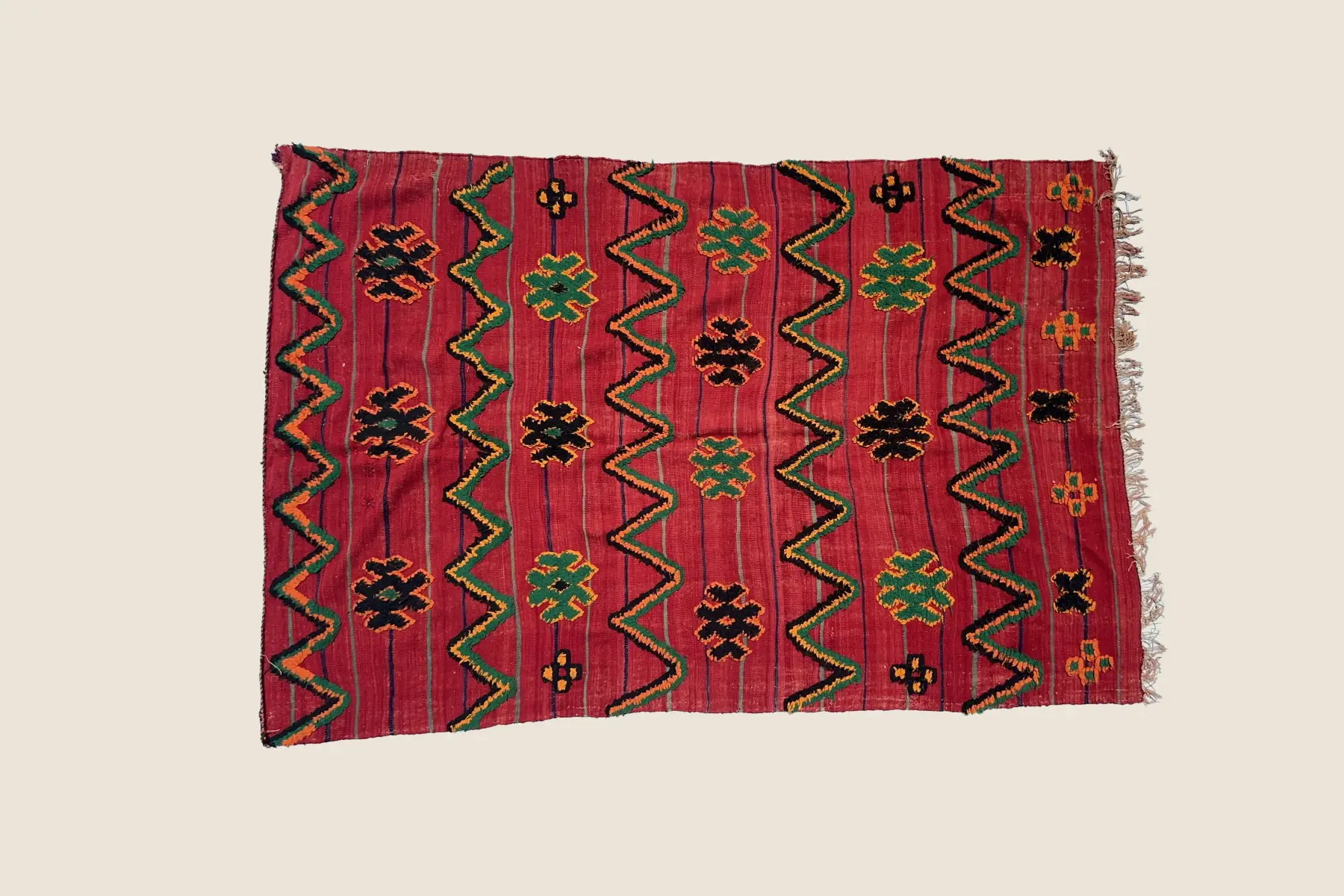 Talsint rug detail showing hand-woven wool texture with warm orange, dark brown, and red geometric motifs