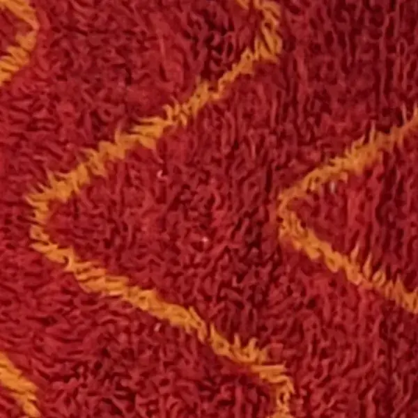 A deep brick red rug with a diamond pattern and small yellow zigzag lines.