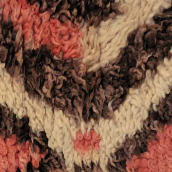 Dark red rug with diamond symbols on a brown background.
