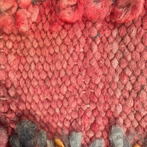 A simple red rug with random wool patches in a coral red shade.