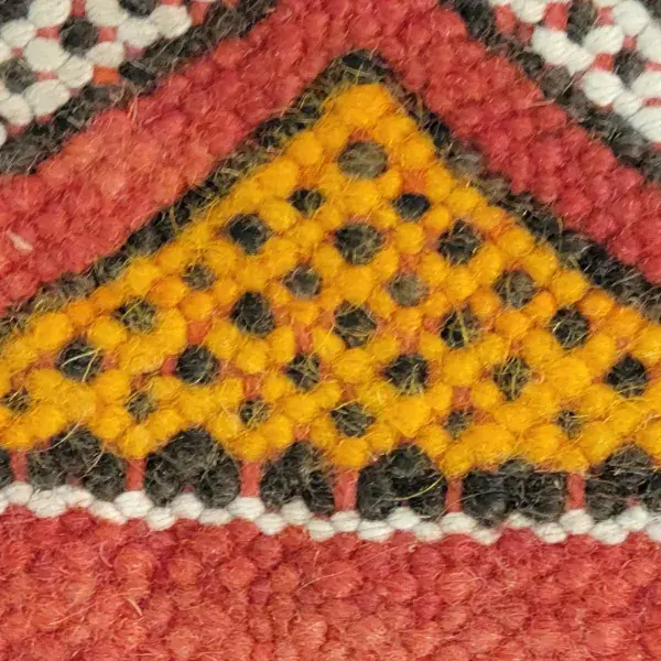 Close-up of a mustard gold kilim art textile with hex code e29f11.